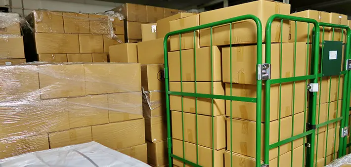 倉庫に積まれた多数の段ボール箱と台車