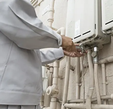 屋外で給湯器を修理する作業員